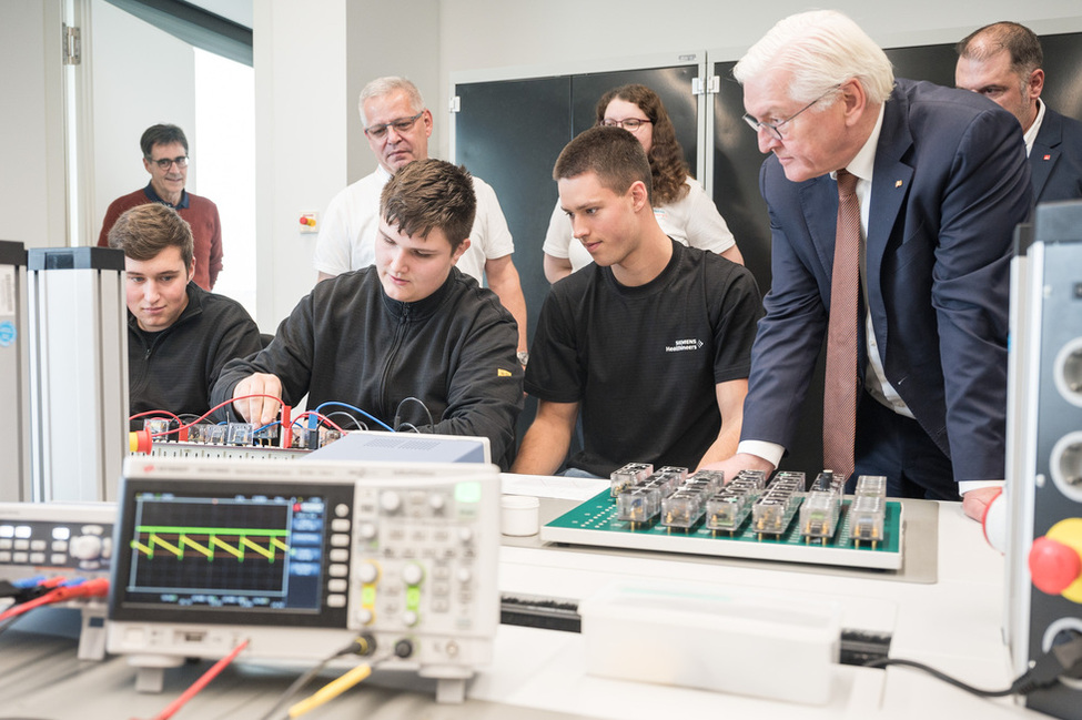 Bundespräsident Frank-Walter Steinmeier lässt sich von Auszubildenden des Elektrolabors der Siemens Healthineers AG ihre Arbeit vorstellen 